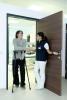 A medical professional talking with a patient as they walk through a doorway on crutches